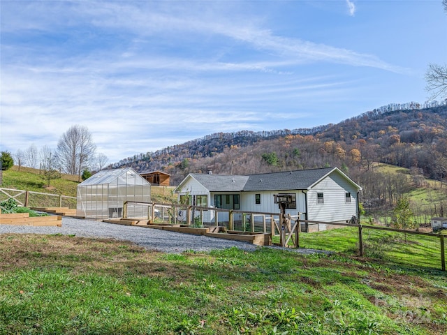 rear view of property with a mountain view and an outdoor structure