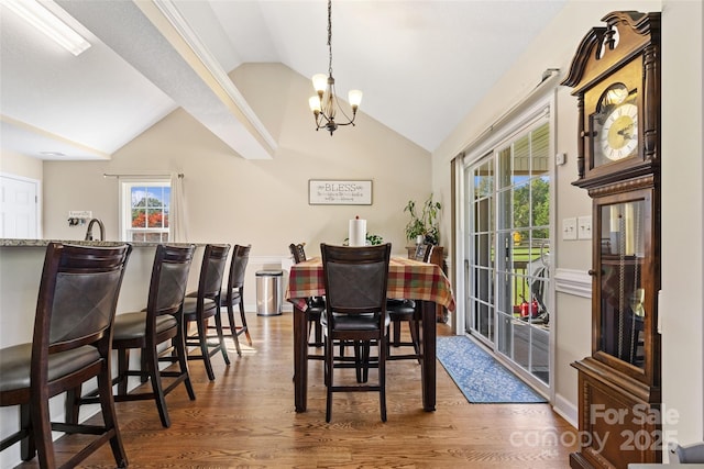 dining space with sink, dark hardwood / wood-style flooring, lofted ceiling, and an inviting chandelier