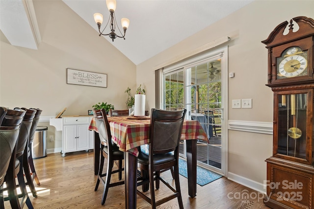 dining room featuring light wood-type flooring, vaulted ceiling, and a notable chandelier