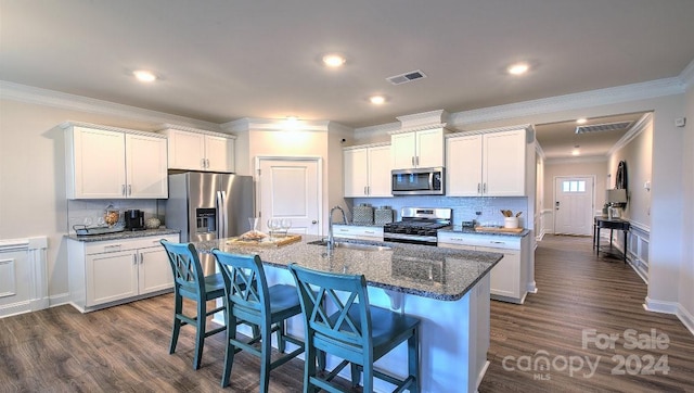 kitchen featuring a center island with sink, crown molding, white cabinetry, appliances with stainless steel finishes, and sink