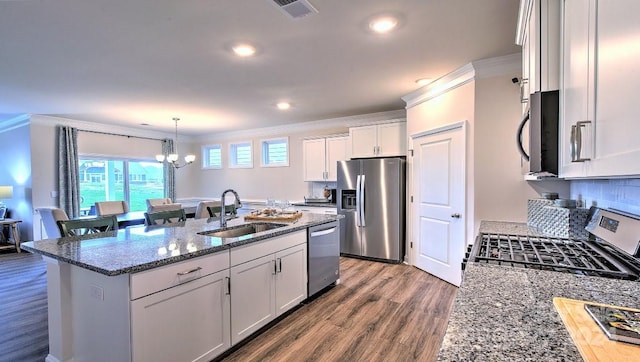 kitchen with white cabinetry, sink, appliances with stainless steel finishes, ornamental molding, and an island with sink