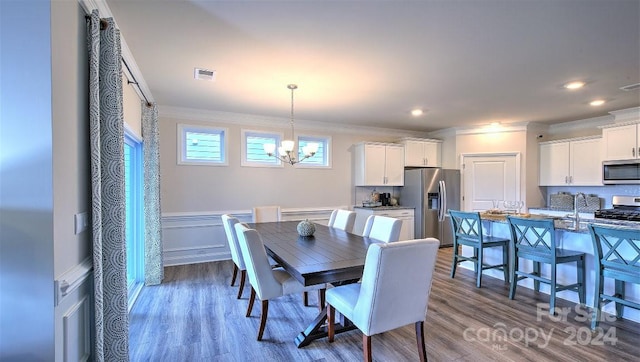 dining space featuring hardwood / wood-style flooring, a chandelier, and crown molding