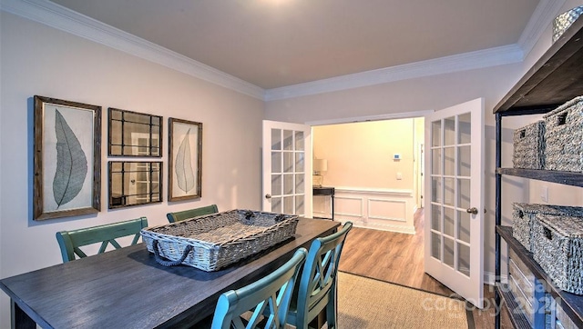 dining room with ornamental molding, french doors, and light hardwood / wood-style floors