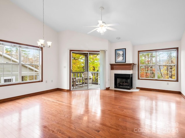 unfurnished living room featuring a wealth of natural light, wood-type flooring, a tile fireplace, and vaulted ceiling