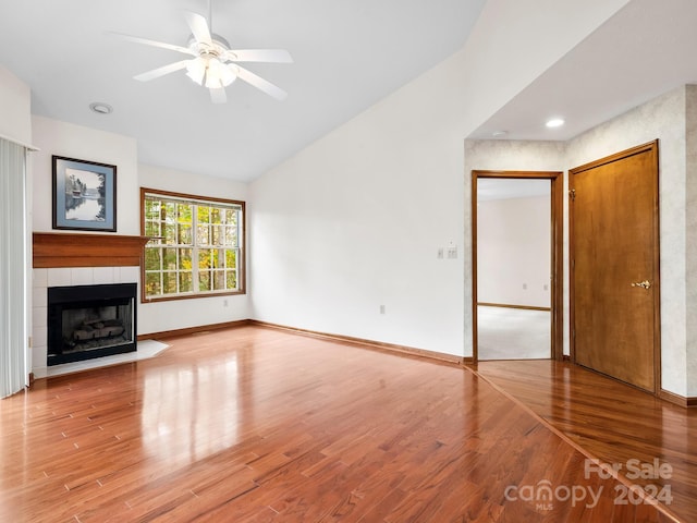 unfurnished living room featuring wood-type flooring, a tile fireplace, ceiling fan, and vaulted ceiling