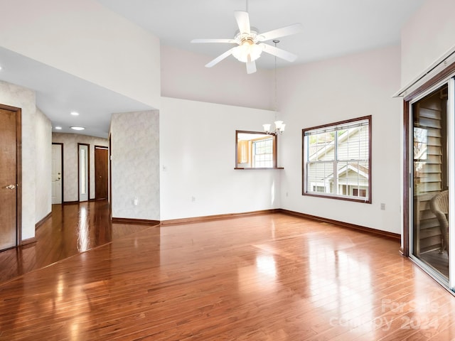 unfurnished room featuring hardwood / wood-style floors and ceiling fan with notable chandelier