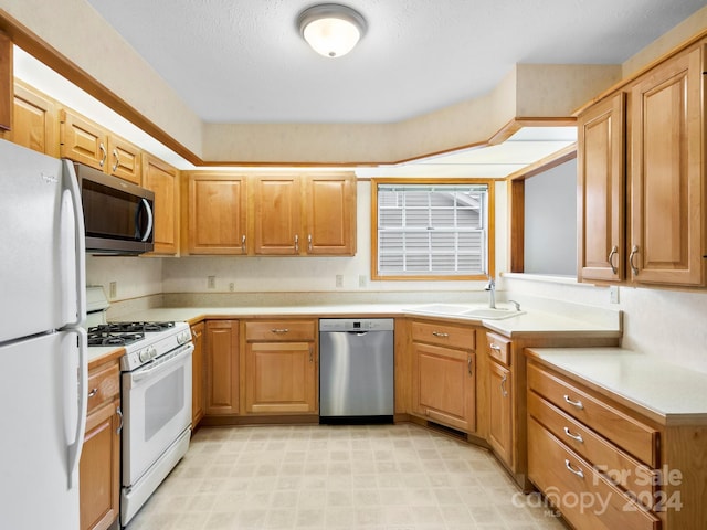 kitchen featuring a textured ceiling, stainless steel appliances, and sink