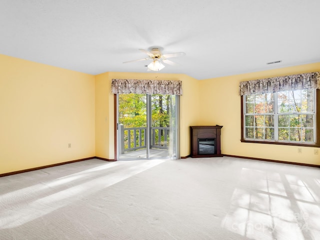 unfurnished living room featuring a wealth of natural light, light carpet, and ceiling fan