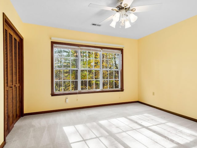 unfurnished bedroom featuring ceiling fan, light carpet, and a closet