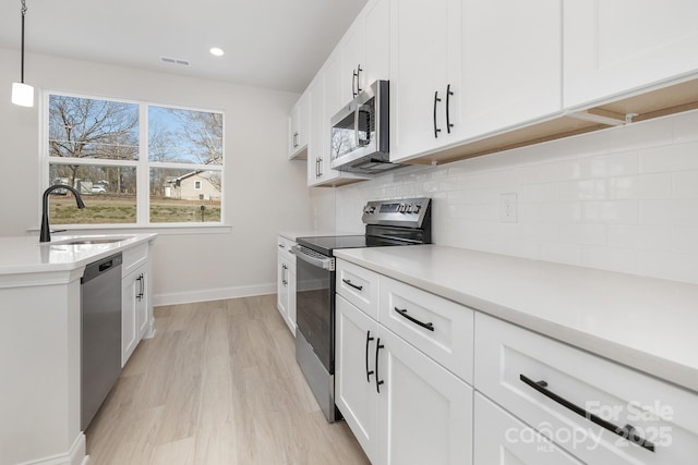 kitchen featuring white cabinetry, appliances with stainless steel finishes, light countertops, and a sink