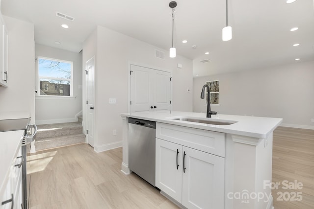 kitchen featuring appliances with stainless steel finishes, light countertops, white cabinetry, pendant lighting, and a sink