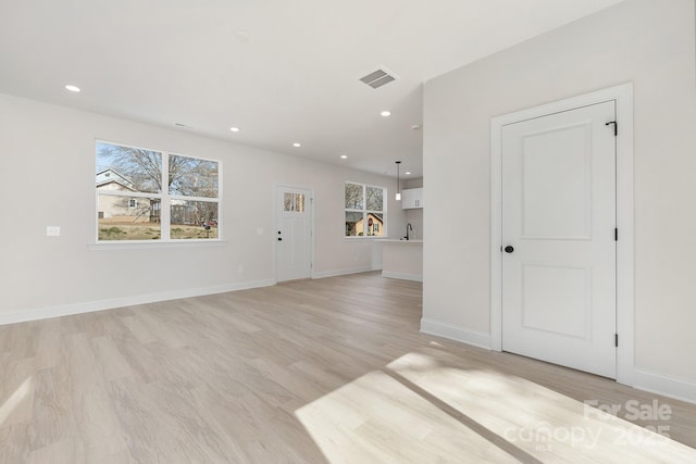 spare room with light wood finished floors, recessed lighting, visible vents, and baseboards