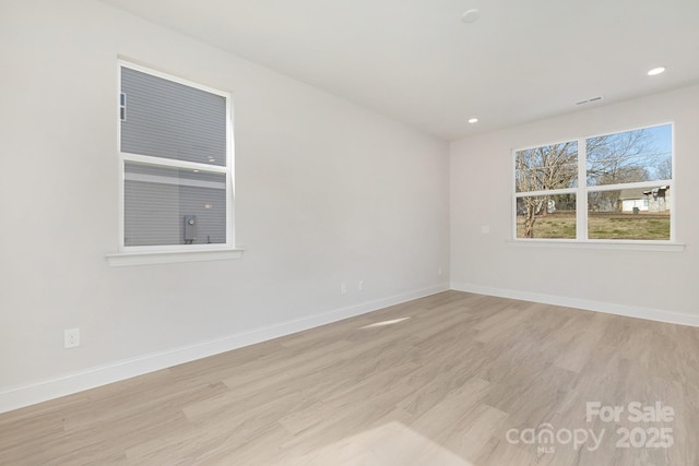 empty room with light wood-type flooring, baseboards, and recessed lighting