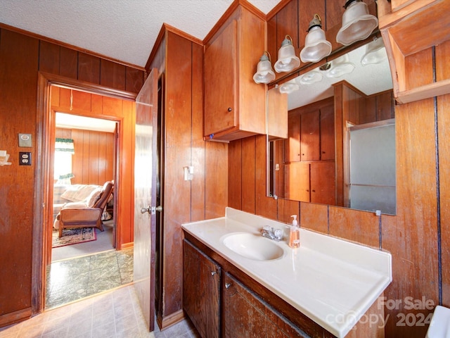 bathroom with a textured ceiling, vanity, and wooden walls