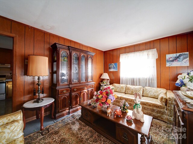 carpeted living room with wood walls