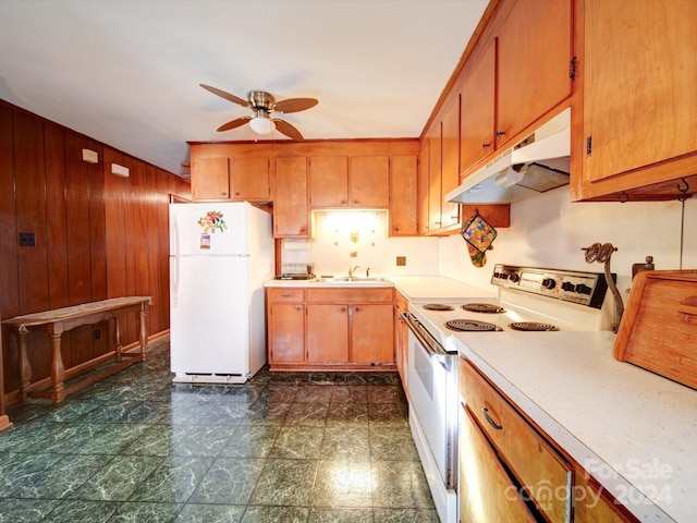 kitchen featuring ceiling fan, wood walls, white appliances, and sink