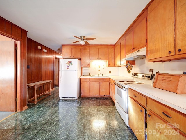 kitchen featuring ceiling fan, white appliances, sink, and wooden walls