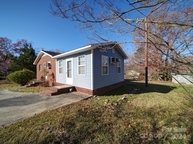 view of property exterior featuring a wall mounted AC and a yard