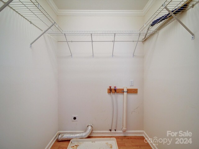 laundry area with electric dryer hookup, wood-type flooring, and ornamental molding