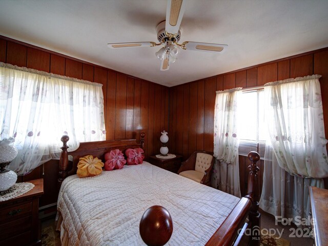 bedroom with ceiling fan and wooden walls