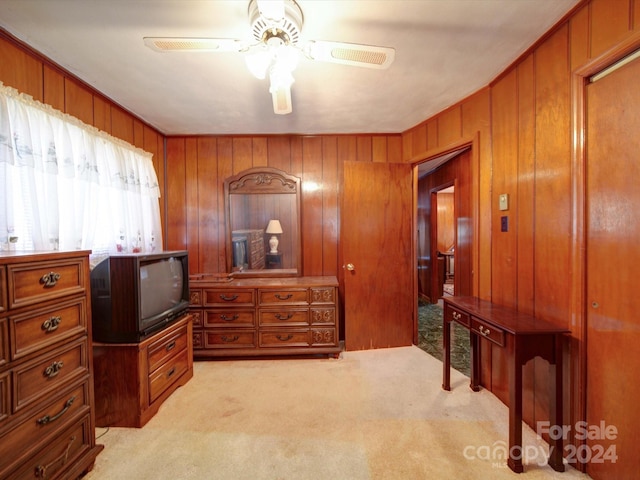 carpeted bedroom with ceiling fan and wooden walls