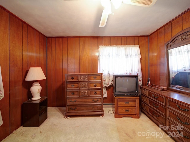 carpeted bedroom with ceiling fan, a baseboard heating unit, and wood walls