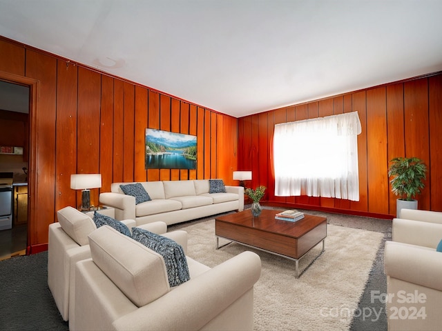 carpeted living room with wooden walls