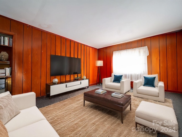 carpeted living room featuring wood walls