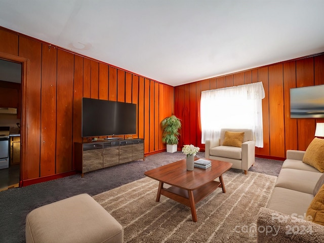 carpeted living room featuring wooden walls