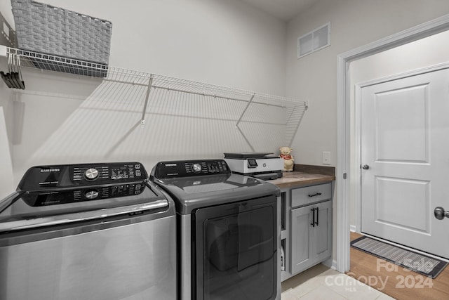 laundry area with separate washer and dryer, cabinets, and light hardwood / wood-style floors