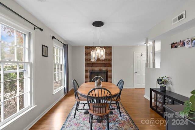 dining space featuring hardwood / wood-style floors, a fireplace, and an inviting chandelier