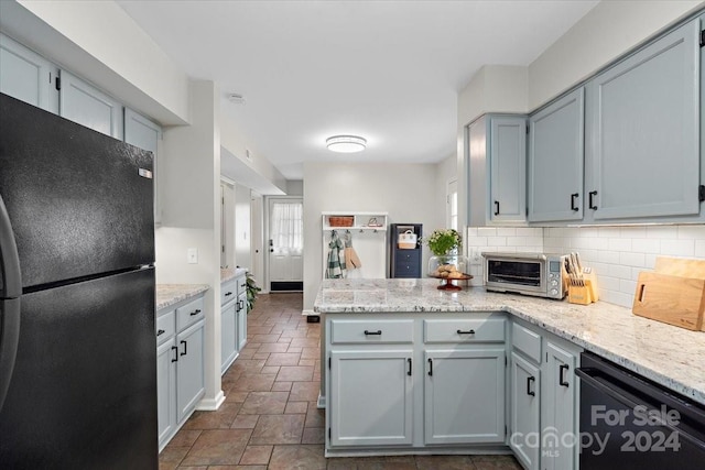 kitchen with black appliances, light stone counters, kitchen peninsula, gray cabinetry, and decorative backsplash