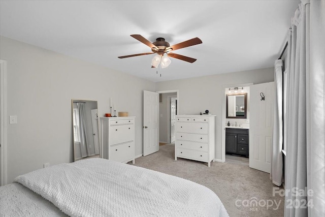 carpeted bedroom with ensuite bathroom, ceiling fan, and sink