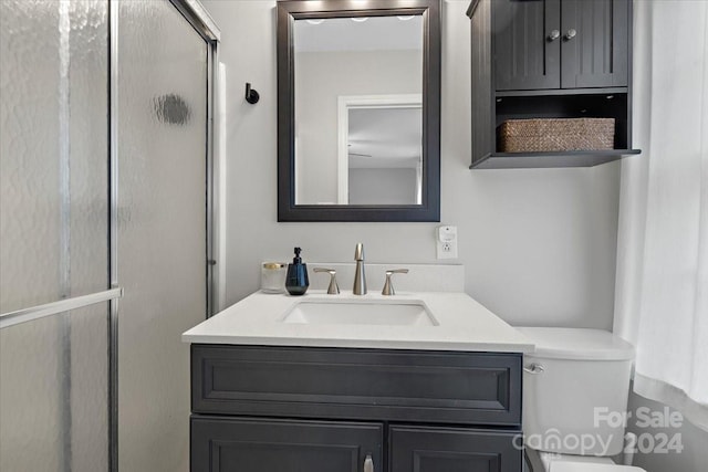 bathroom with toilet, vanity, and a shower with door