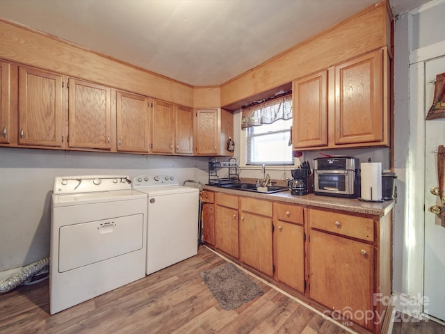 clothes washing area featuring washer and clothes dryer, sink, and light hardwood / wood-style flooring