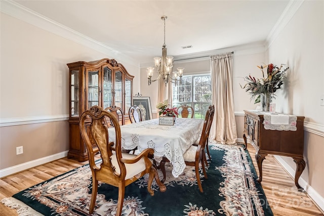 dining room with light hardwood / wood-style floors, an inviting chandelier, and ornamental molding