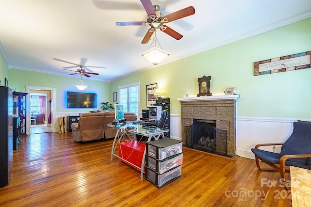 living room with hardwood / wood-style floors, ceiling fan, ornamental molding, and a fireplace