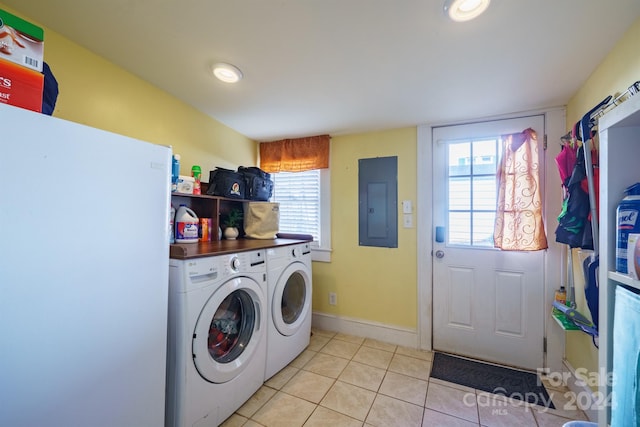 clothes washing area with light tile patterned floors, electric panel, and washing machine and clothes dryer