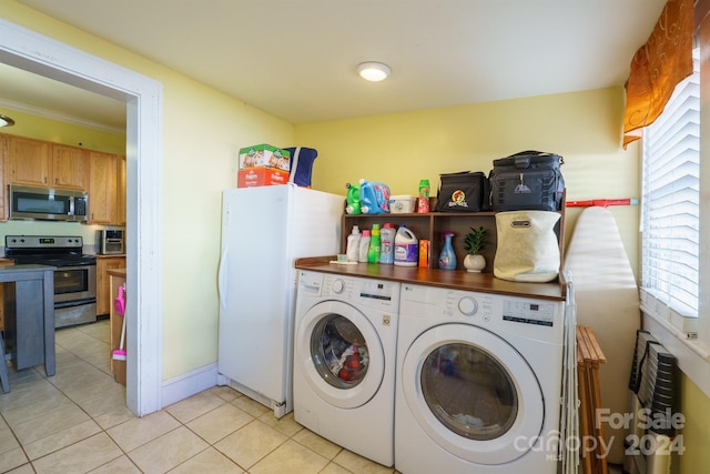 laundry area featuring light tile patterned floors, washing machine and dryer, and ornamental molding