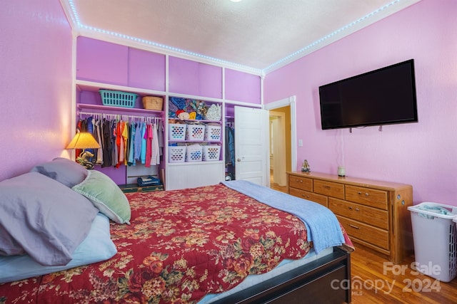 bedroom with hardwood / wood-style floors, a closet, and crown molding