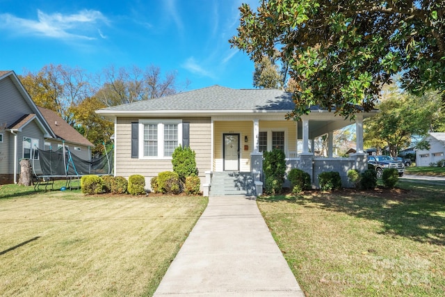 bungalow-style house featuring a front lawn, covered porch, and a trampoline