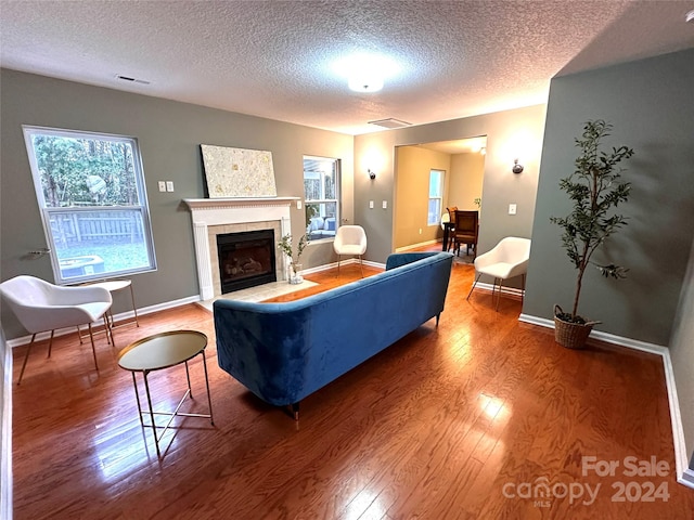 living room with a tile fireplace, hardwood / wood-style floors, and a textured ceiling