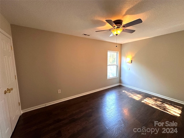 unfurnished room with ceiling fan, dark wood-type flooring, and a textured ceiling