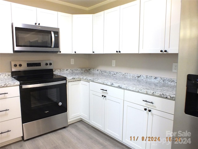 kitchen with stainless steel appliances, light stone counters, ornamental molding, light hardwood / wood-style flooring, and white cabinets