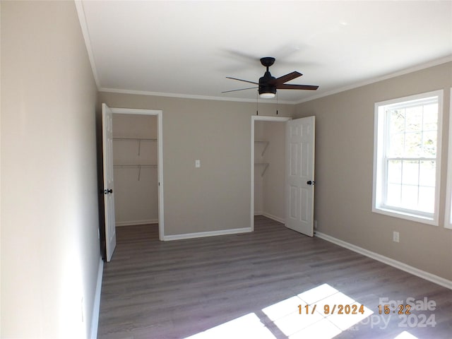 unfurnished bedroom featuring a closet, a spacious closet, crown molding, light hardwood / wood-style floors, and ceiling fan