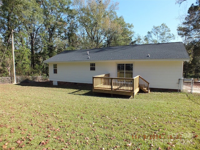 rear view of house featuring a lawn and a deck