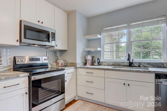 kitchen featuring stainless steel appliances, a wealth of natural light, white cabinetry, and sink