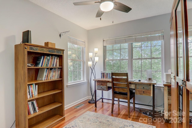 office space featuring ceiling fan, a textured ceiling, light hardwood / wood-style floors, and plenty of natural light