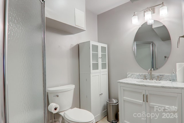 bathroom featuring toilet, an enclosed shower, and vanity