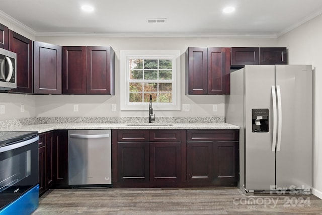 kitchen with stainless steel appliances, sink, ornamental molding, light stone countertops, and light hardwood / wood-style flooring